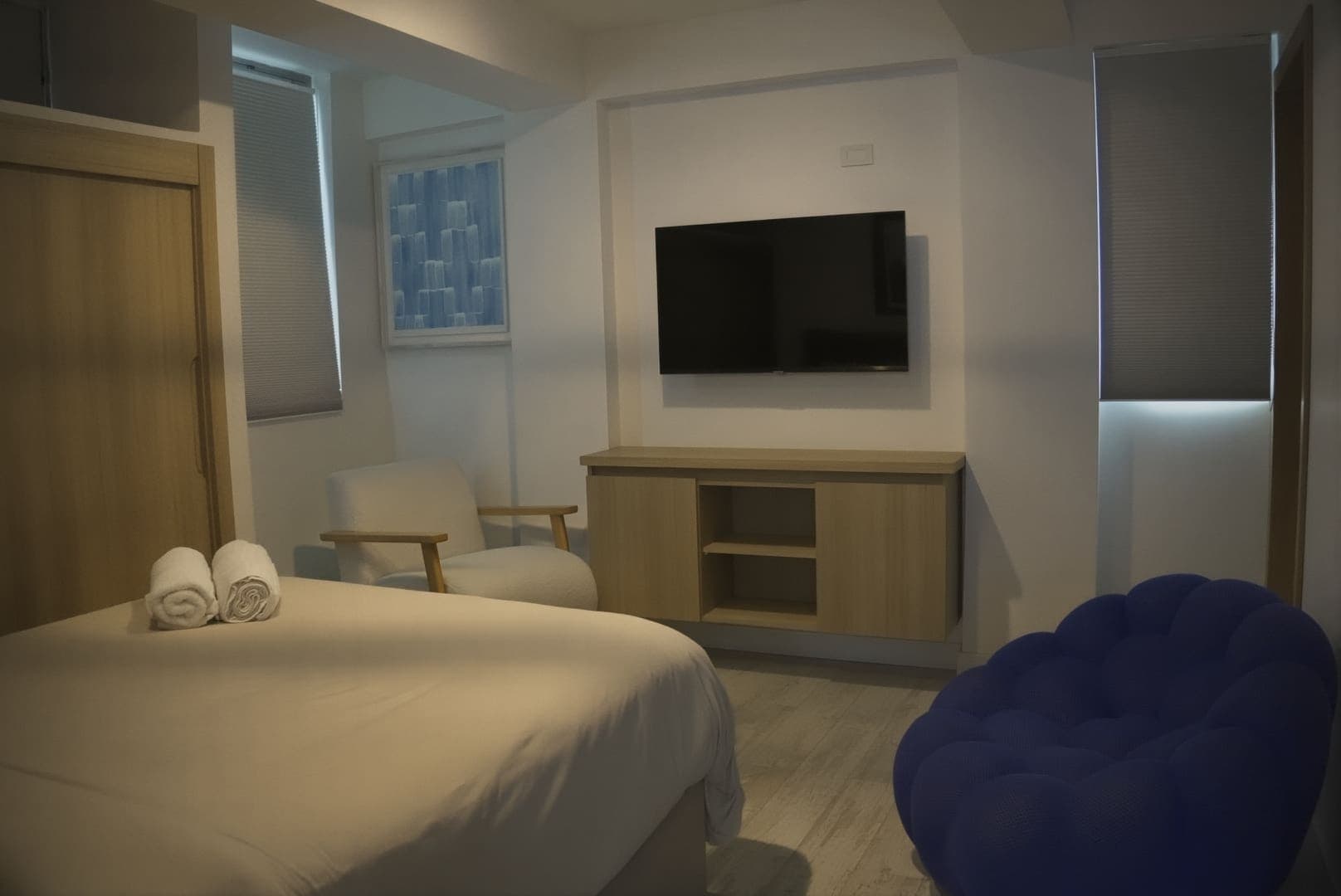 Habitación con televisión, cómoda de madera y butaca