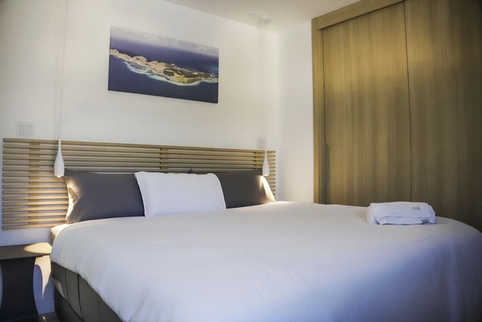 Habitación principal con cama grande, cabecera de listones y armario de madera