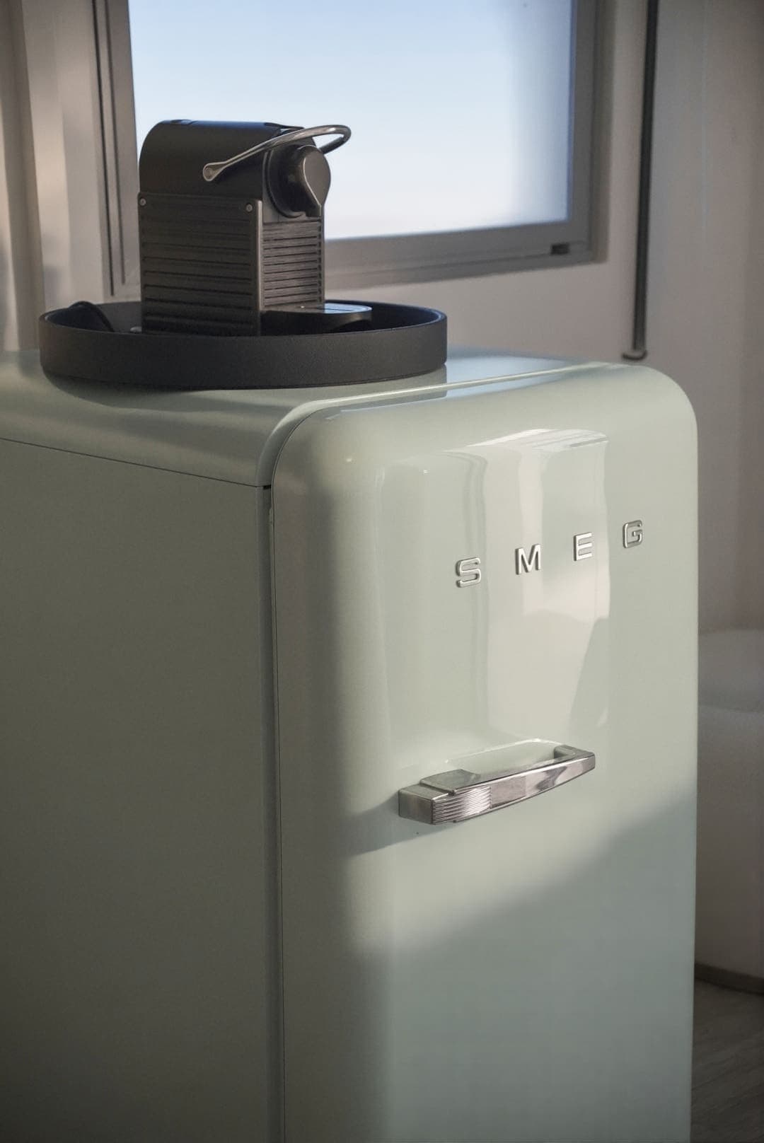 Refrigerador retro verde agua con una cafetera encima